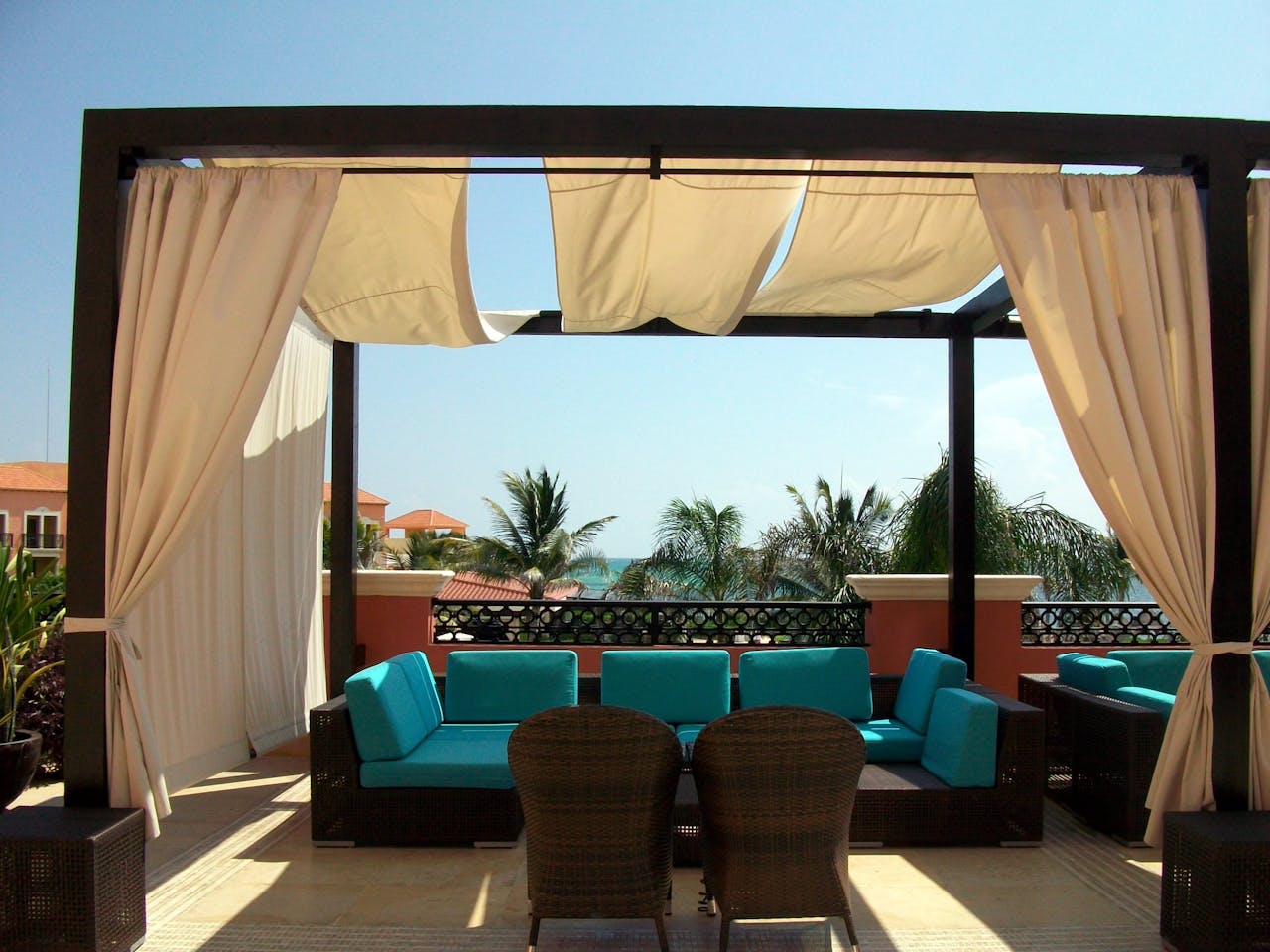 Elegant outdoor seating area on a sunlit rooftop overlooking the ocean.